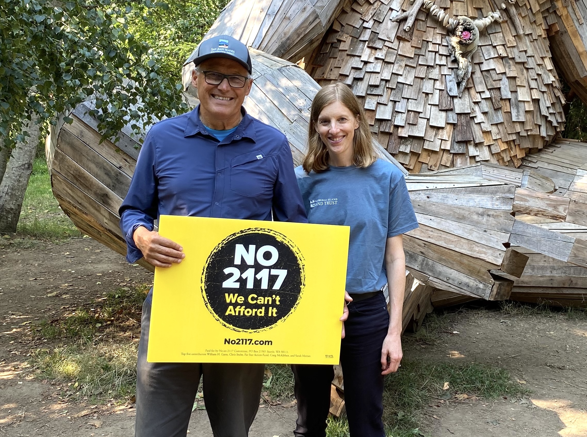 Governor Jay Inslee and Nora Nickum posing with a sign that says "NO 2117, We Can't Afford It"